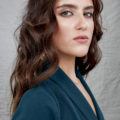 How to style long hair: Studio photo of a brunette woman with voluminous Victoria's Secret waves, wearing a teal blazer dress