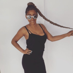 woman with long cornrow braided ponytail wearing black vest dress and sunglasses holding up ponytail