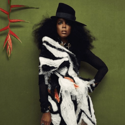 Kelly Rowland for Schon magazine photoshoot with natural hair and a hat weaering a black and white and orange outfit
