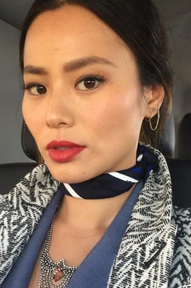 Jamie Chung selfie wearing a black and white coat zig-zag coat and a neck scarf with dark brown hair worn in an updo