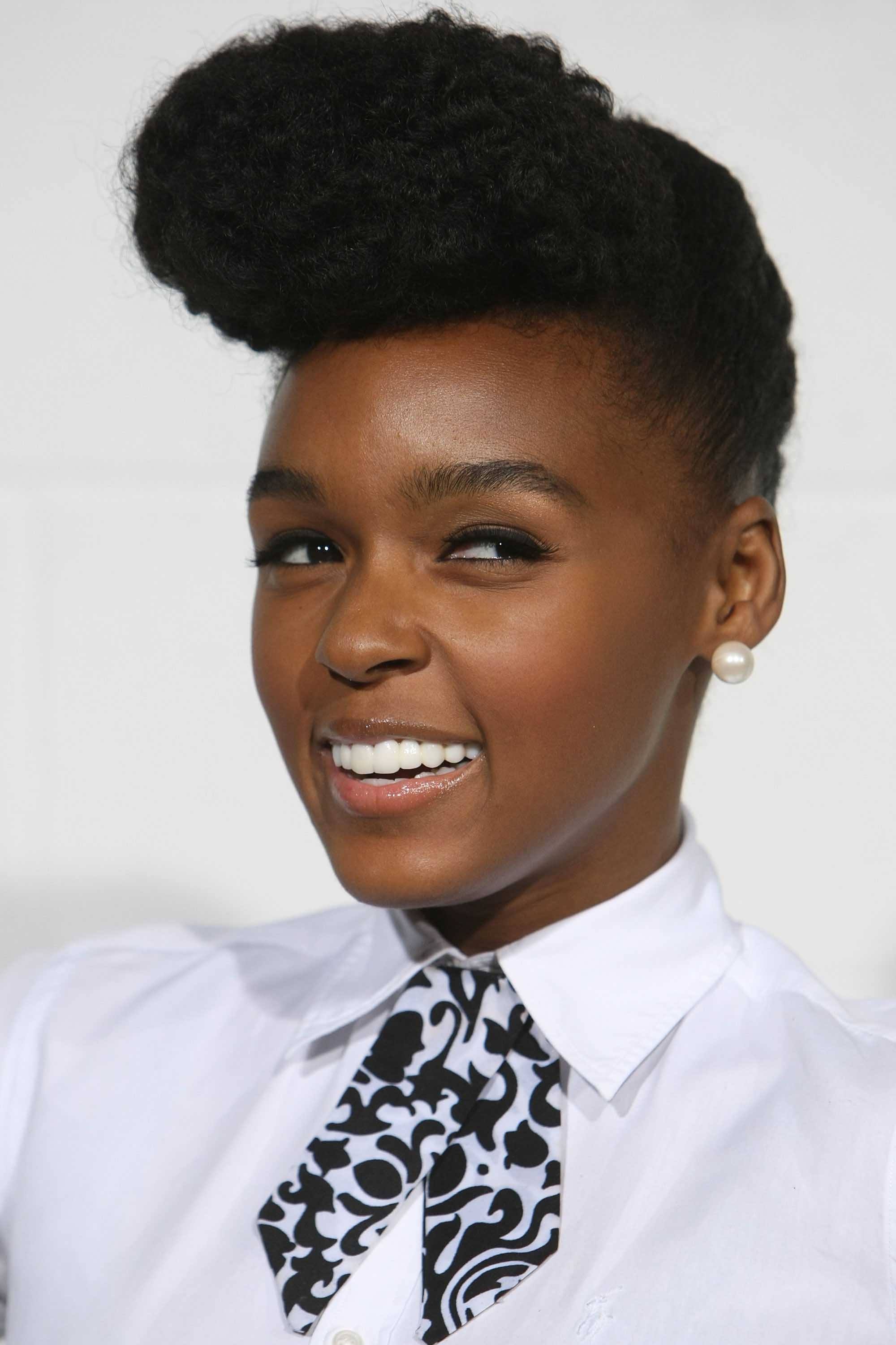 Black history month hairstyles: Close up shot of Janelle Monae with a dark brown natural pompadour, wearing pussybow shirt and posing on the red carpet