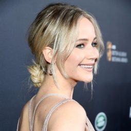 Jennifer Lawrence on the red carpet wearing a strapy back dress with a low bun updo in a light blonde colour