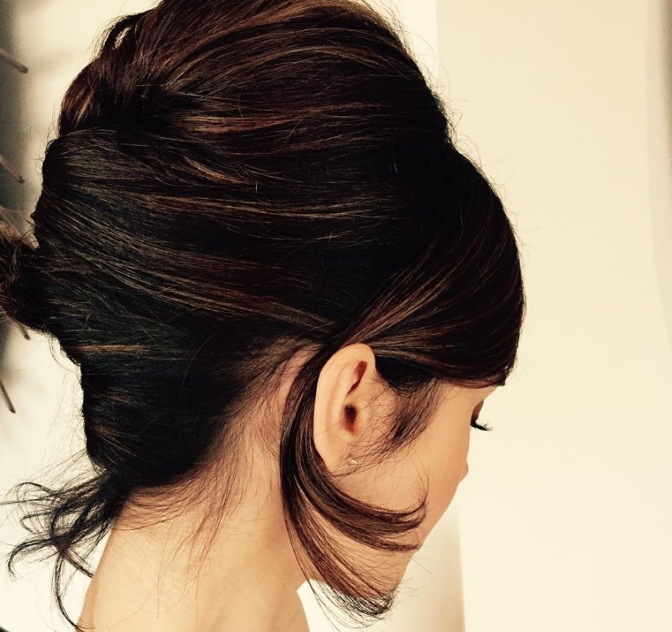 back view of actress Lily Collins with her dark brown hair worn in a french twist updo and one piece of hair tucked behind her ear