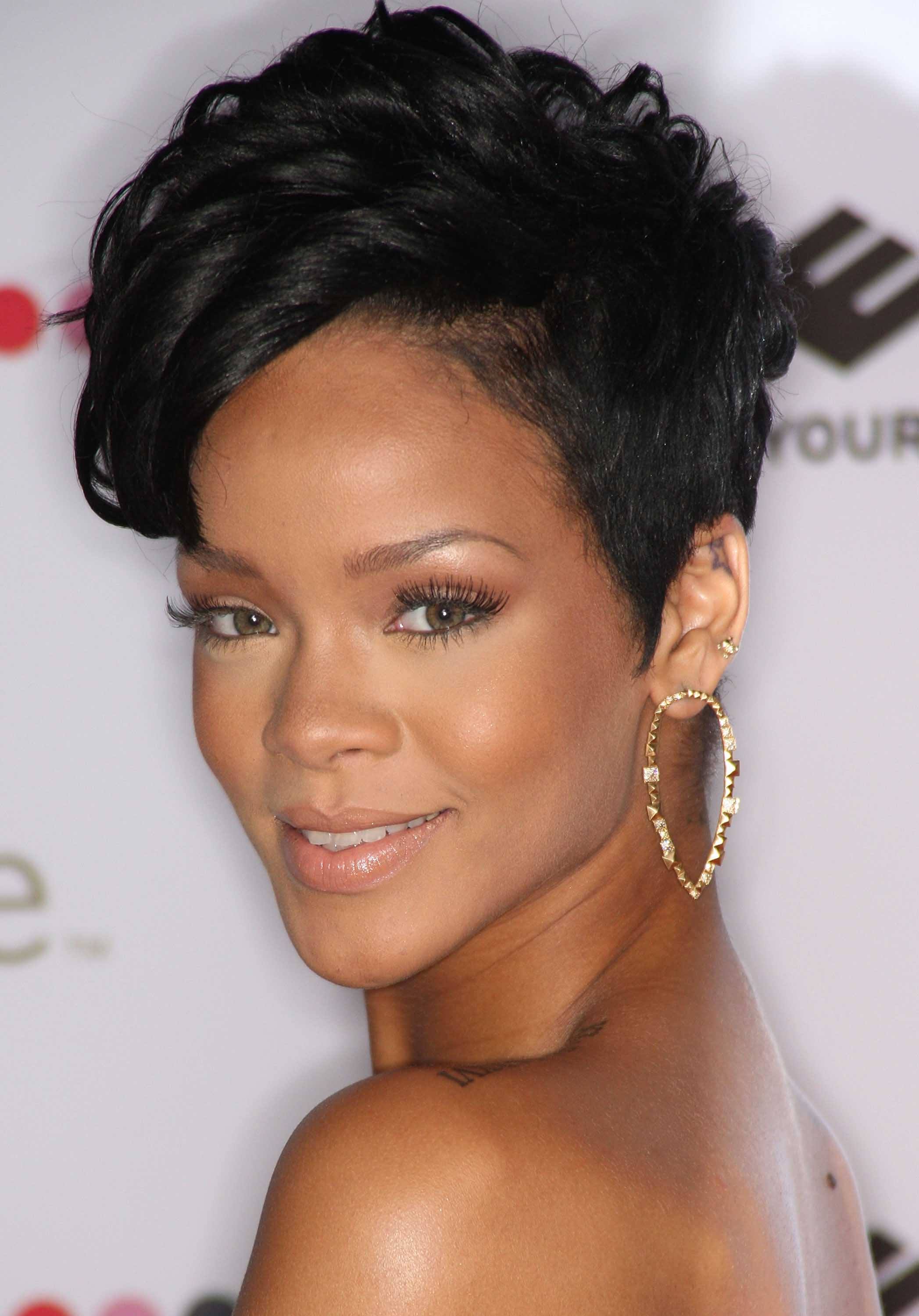 Black history month hairstyles: Close up shot of Rihanna with a dark brown wavy pixie with side-swept fringe, wearing golden hoop earring on the red carpet