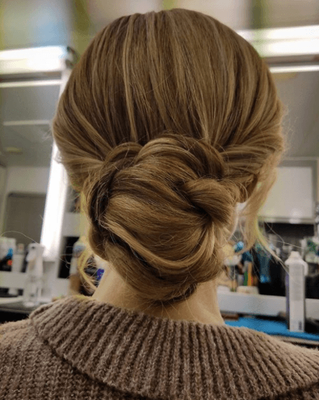 back view of a woman with her hair in a bun with dark honey blonde hair colour - blonde brown hair