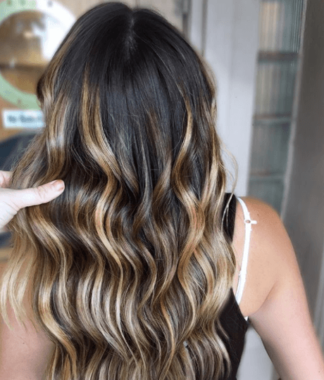 back view image of a woman's with dark brown wavy hair with shades of blonde - blonde brown hair