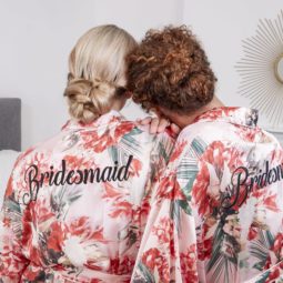 wedding chignon: back view of two bridesmaids, one with blonde straight hair and the other with curly golden brown hair both with their hair in low chignon wedding hairstyles