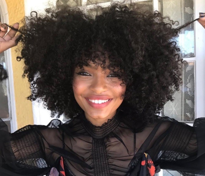 close up shot of yara with curly diana ross curls with bangs posing