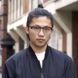 street style shot of an asian man with a top knot brown hair short sides long top