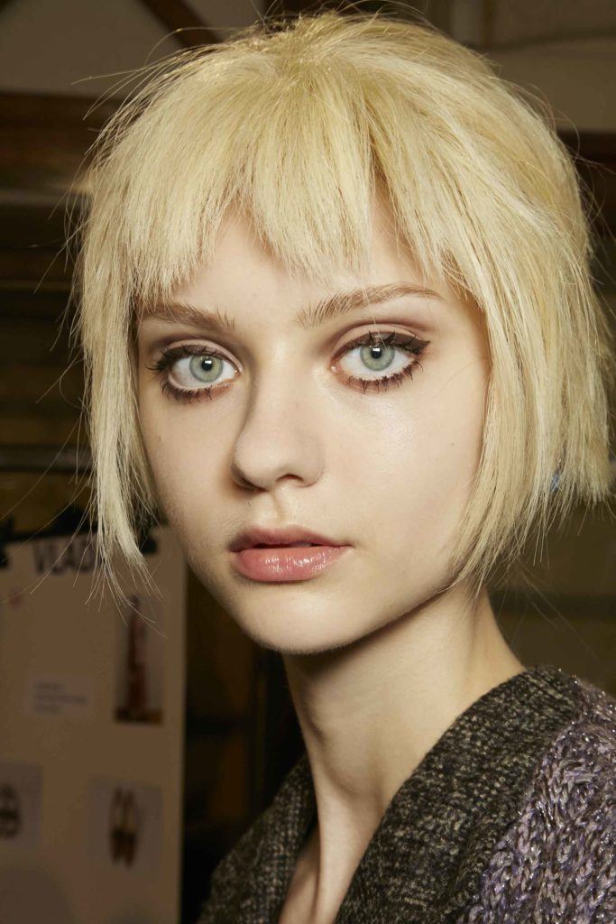 close up shot of a model with flaxen blonde hair cut into a choppy bob and fringe