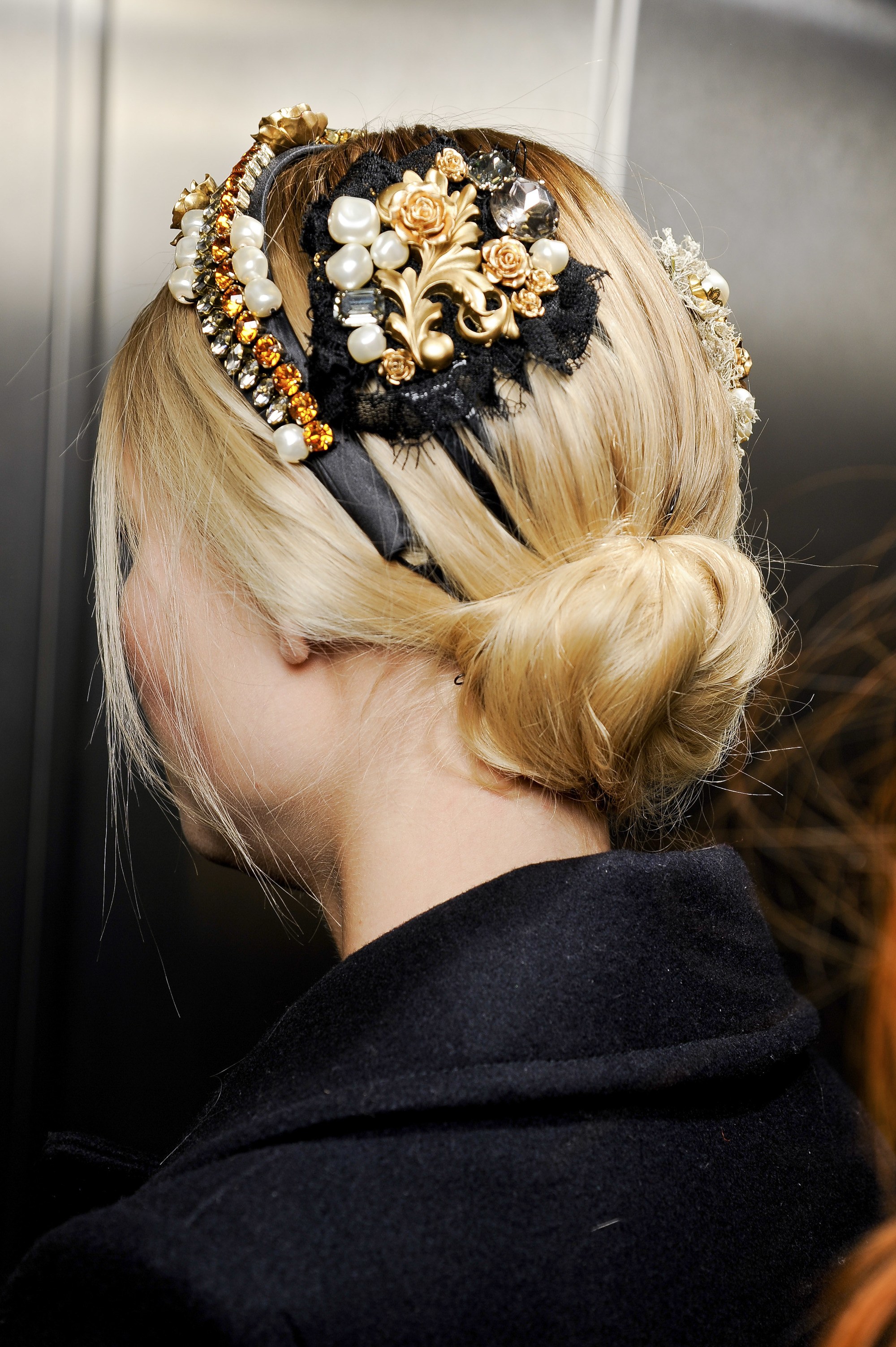 updos for long hair: model with blonde straight hair in low bun with floral accessory