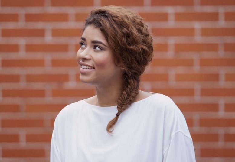 Fishtail braid: A young black woman with curly brown hair with a fishtail plait