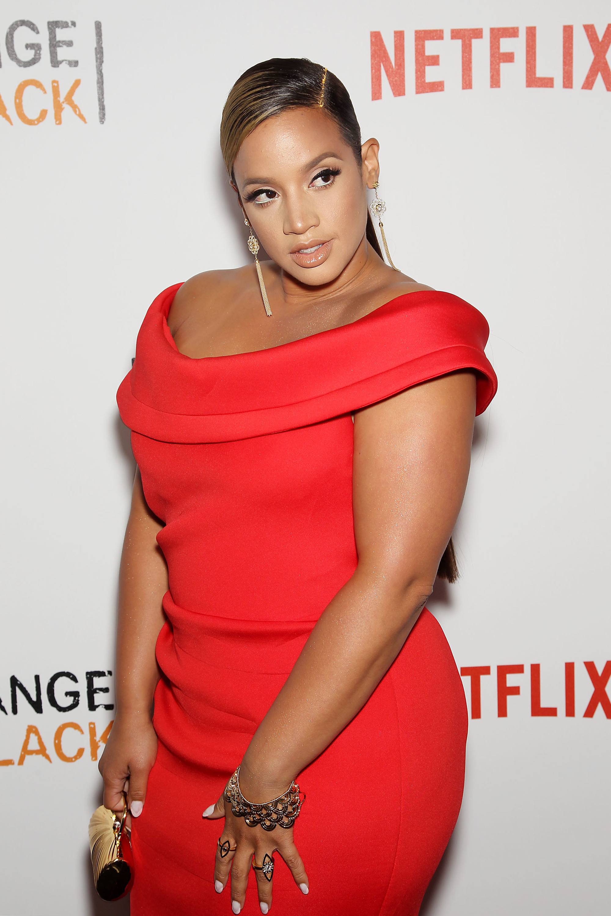 Dascha Polanco on the red carpet with her dark brown hair styled into a long, sleek ponytail, with a golden glitter hair parting, wearing a red dress