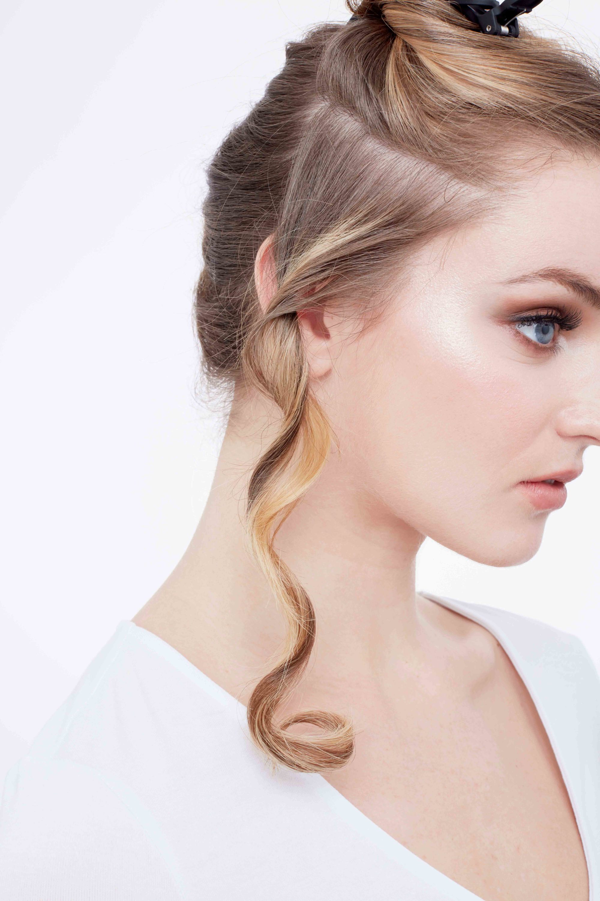 How to curl your hair: Close-up of a blonde woman with her hair twisted and clipped up with a single piece of curled hair