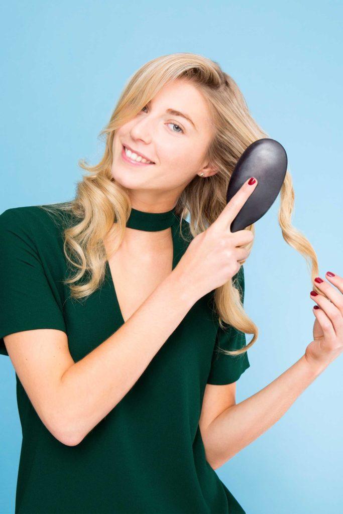 Blonde girl brushing her curls out