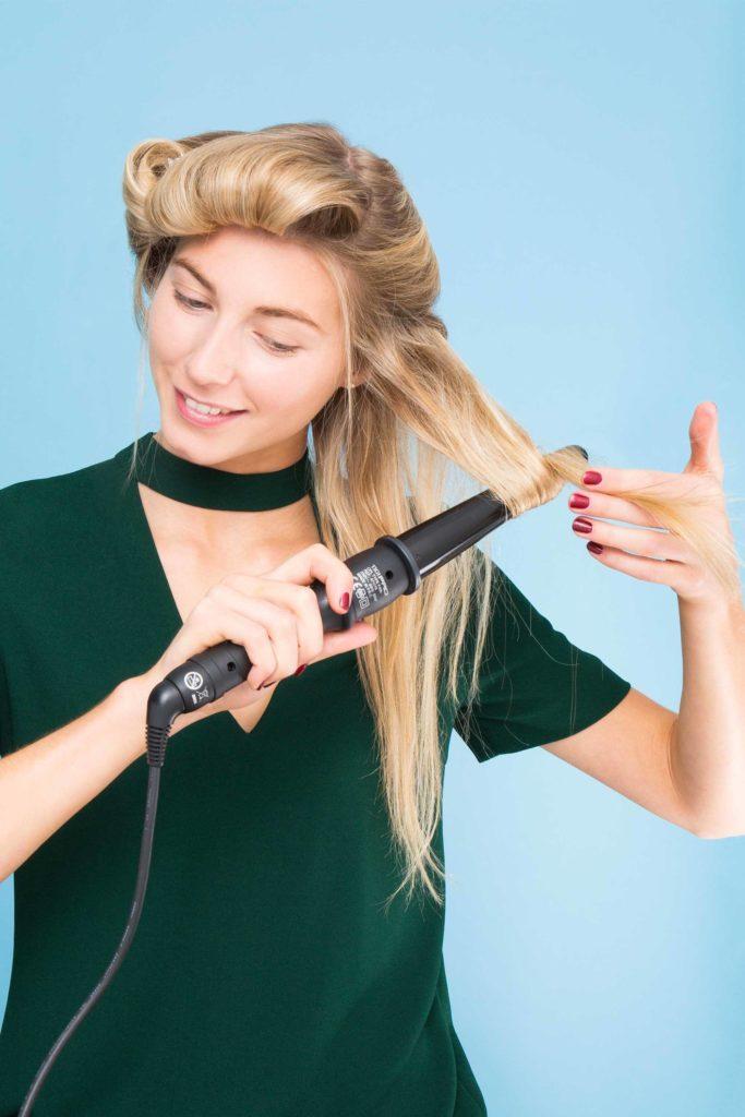 Blonde haired woman curling the rest of her hair