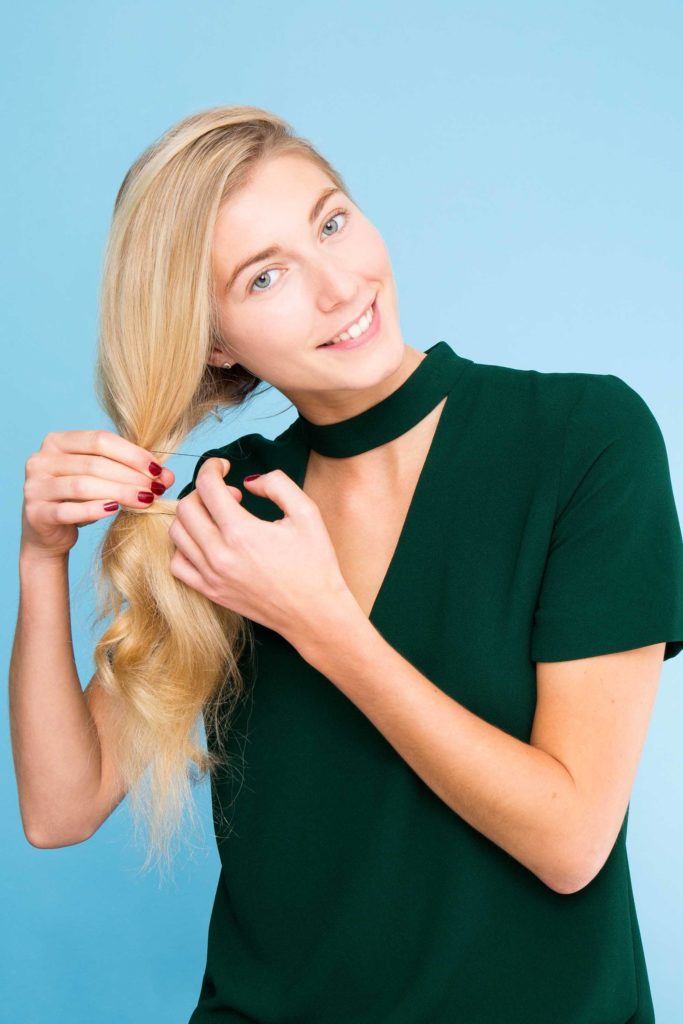 Blond girl creating a ponytail