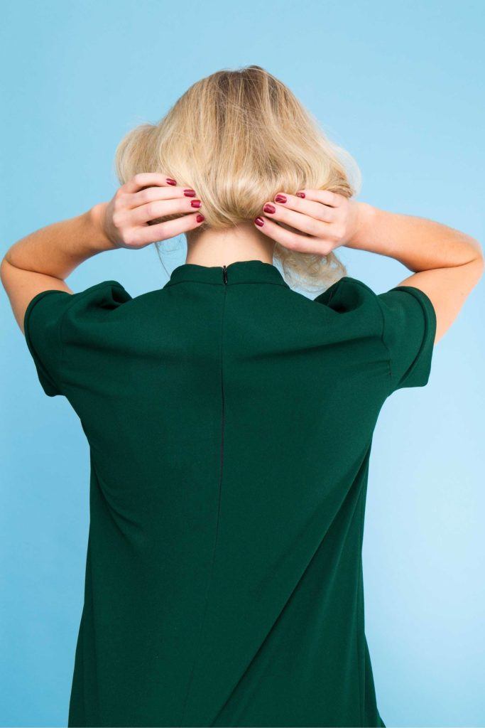 a rear view of a blonde woman tucking in her hair