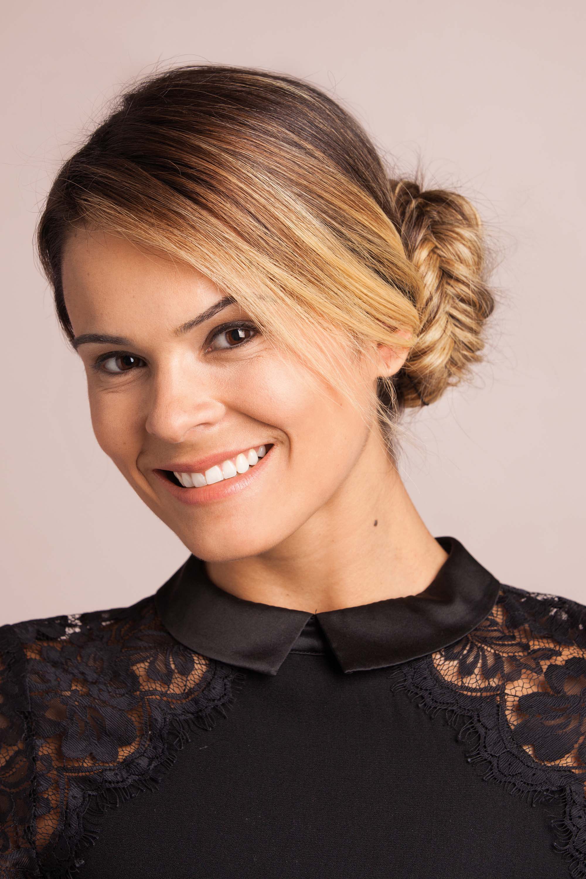 A young woman with blonde highlighted hair with a side fishtail braided bun