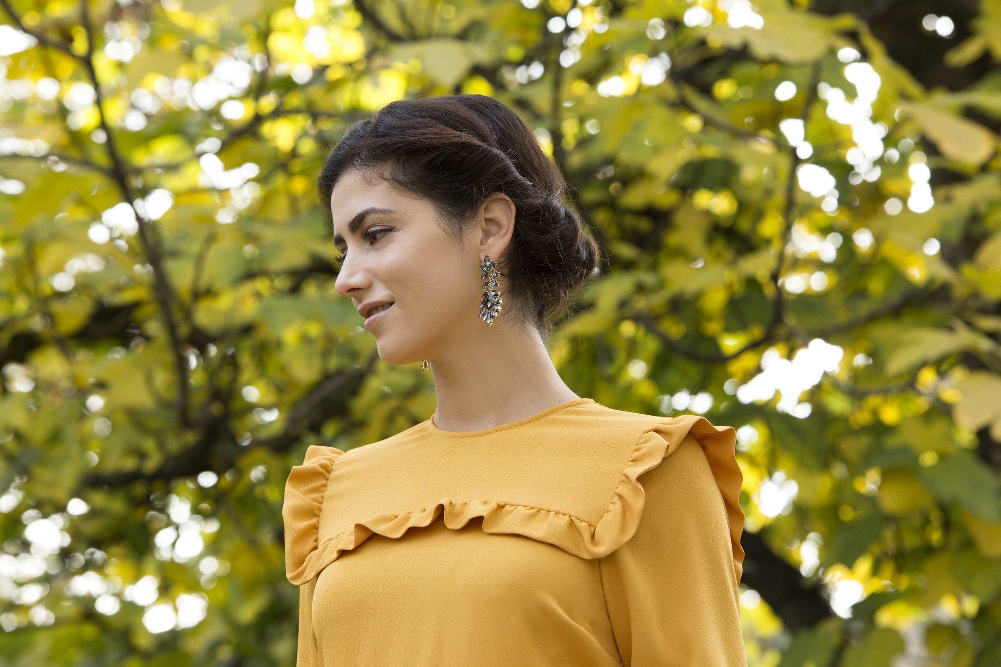 updos for long hair: model with brown hair in a gibson tuck hairstyle wearing a yellow frilly dress.