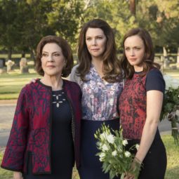 Netflix's Emily, Lorelai and Rory from Gilmore Girls stood in a cemetery each with brown hair worn in waves