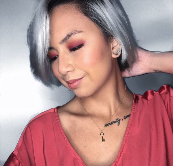 Instagram pic of @erikaseas touching her grey short hair and looking down