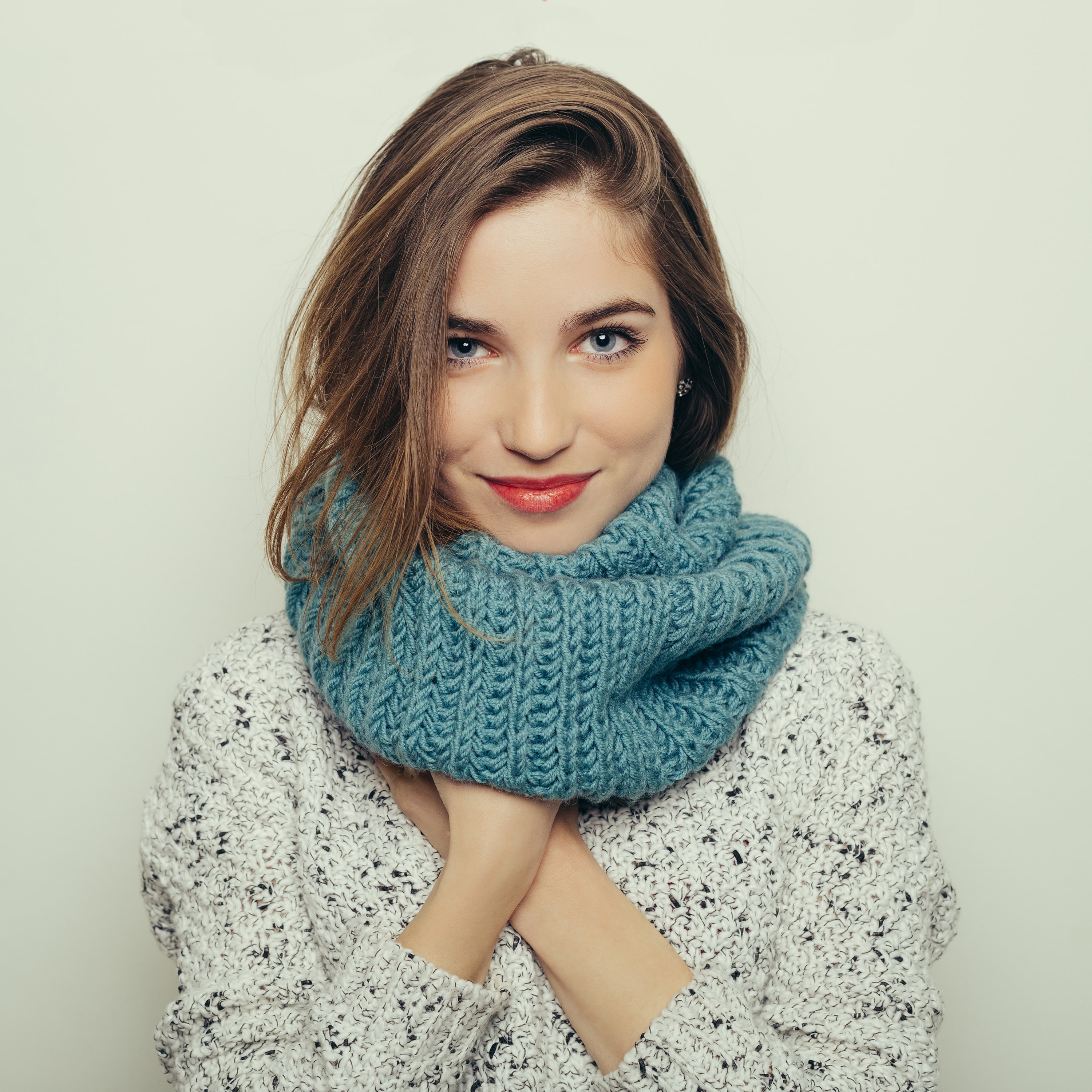 Hair mask: Shot of a young woman with chocolate brown hair, wearing a blue scarf and floral print top in a studio