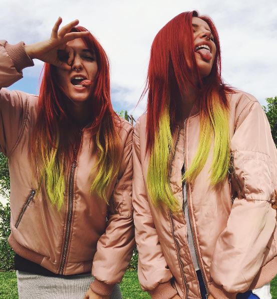 Bella with twin sister Dani Thorne posing wearing pink jackets and long straight hair dyed in a red to yellow ombre