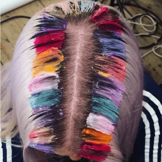 woman with blonde hair getting rainbow roots applied to her hair