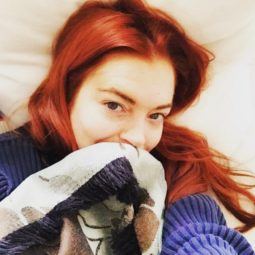 Lindsay Lohan selfie with vibrant read hair wearing a blue and white sweater