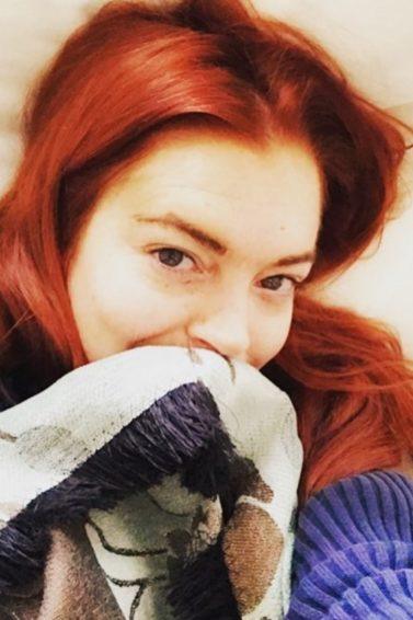 Lindsay Lohan selfie with vibrant read hair wearing a blue and white sweater