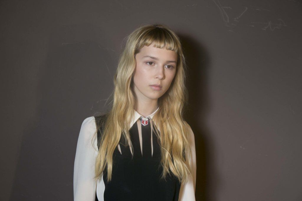 model wearing a black and white outfit with her long blonde hair worn in loose waves with a micro fringe cut in