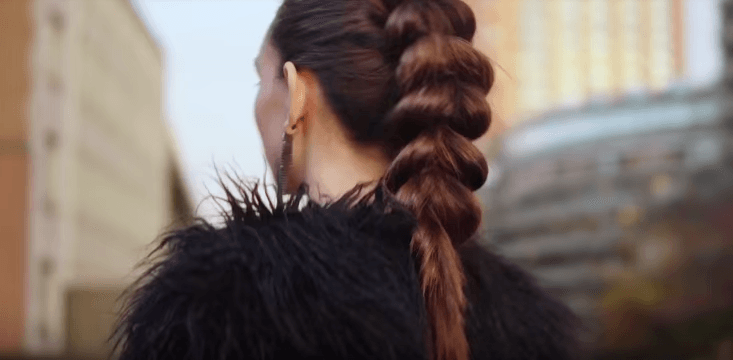 Pull through braid brunette girl standing outside with her back to camera