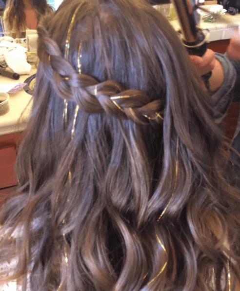back of a woman's head with brown hair in a braid with gold tinsel hair