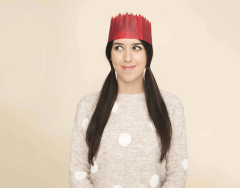 Christmas hairstyles: Woman with long dark hair in pigtails, wearing a Christmas hat and a spotted knitted jumper.