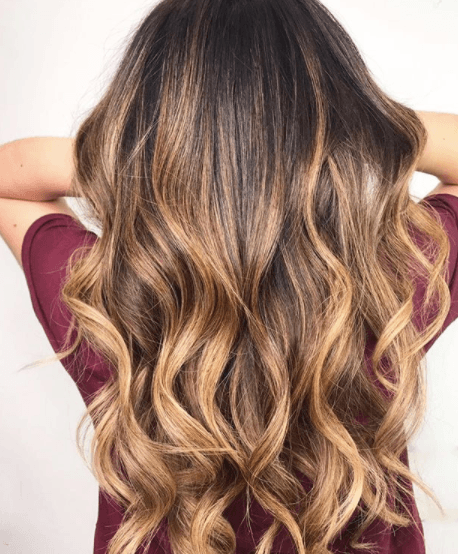 back view of a woman with long curled hair - tiger eye hair colour