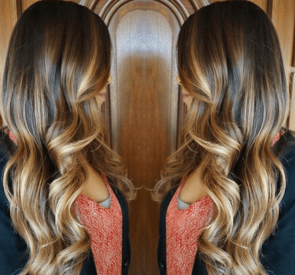 mirror view image of a woman with her hair worn long and wavy