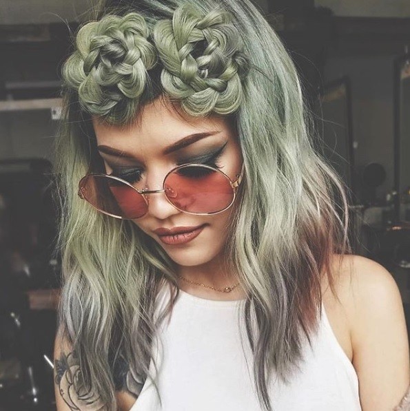 woman with shoulder length wavy green succulent hair with braided space buns wearing red circular sunglasses
