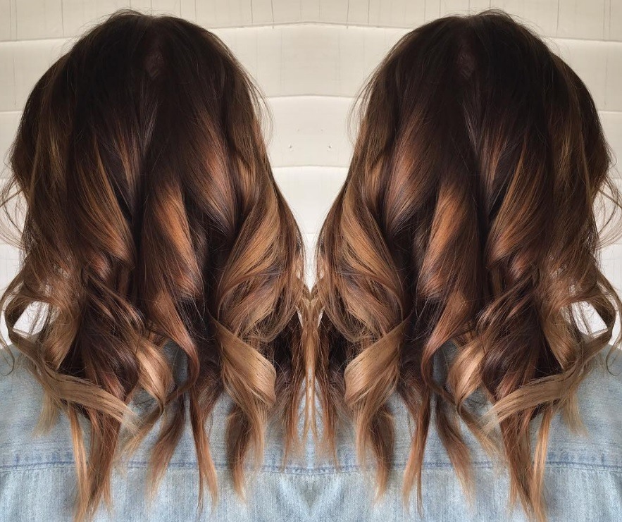 back view image of a woman with curly hair and balayage tiger eye hair colour