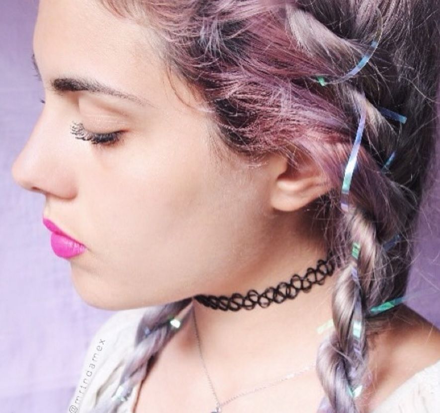 side view image of a woman with pink braided hair with tinsel intertwined in the hair