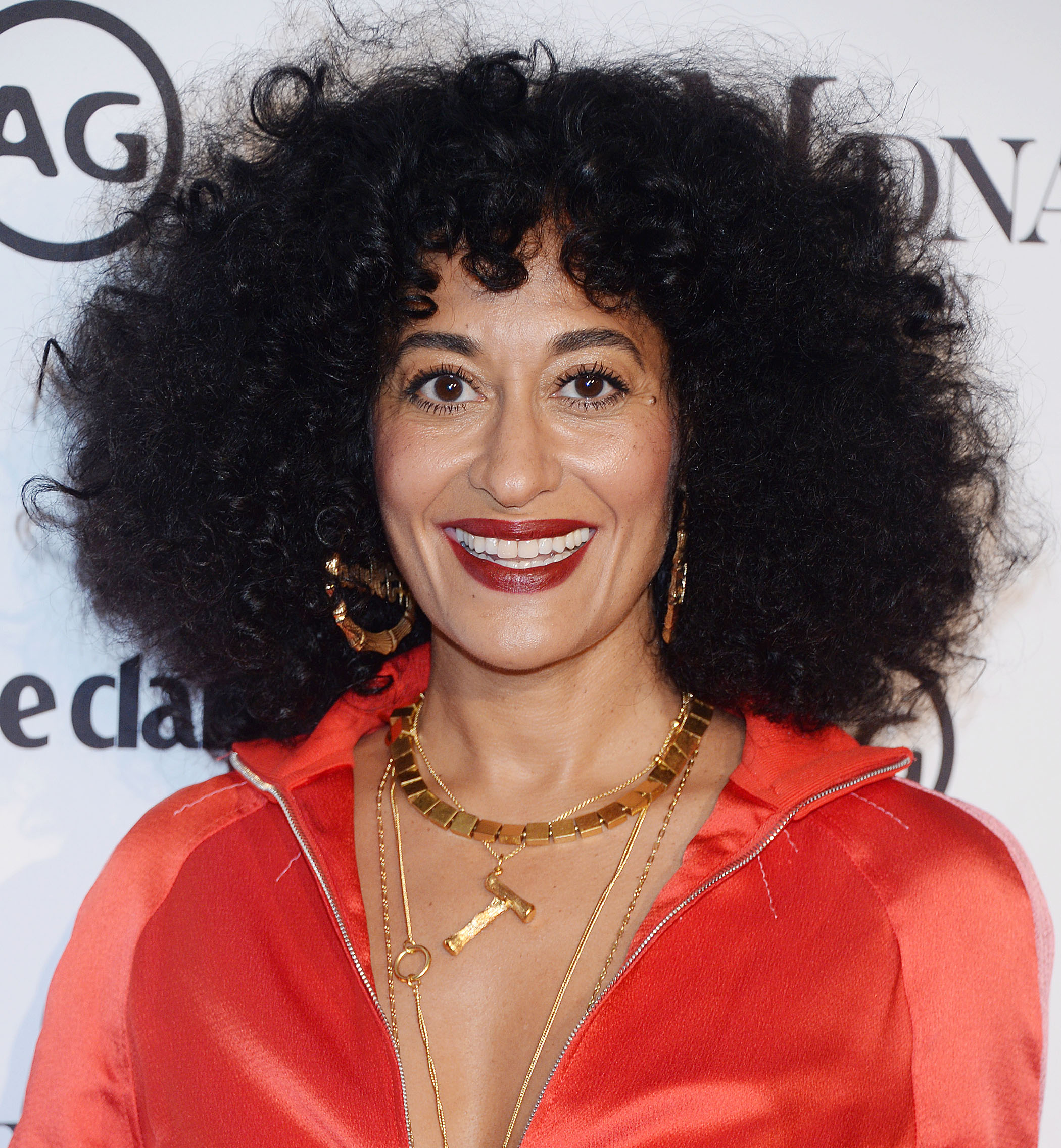 Curly hair hairstyles: Tracee Ellis Ross with dark brown shoulder length naturally curly hair with short micro fringe wearing red satin dress on red carpet