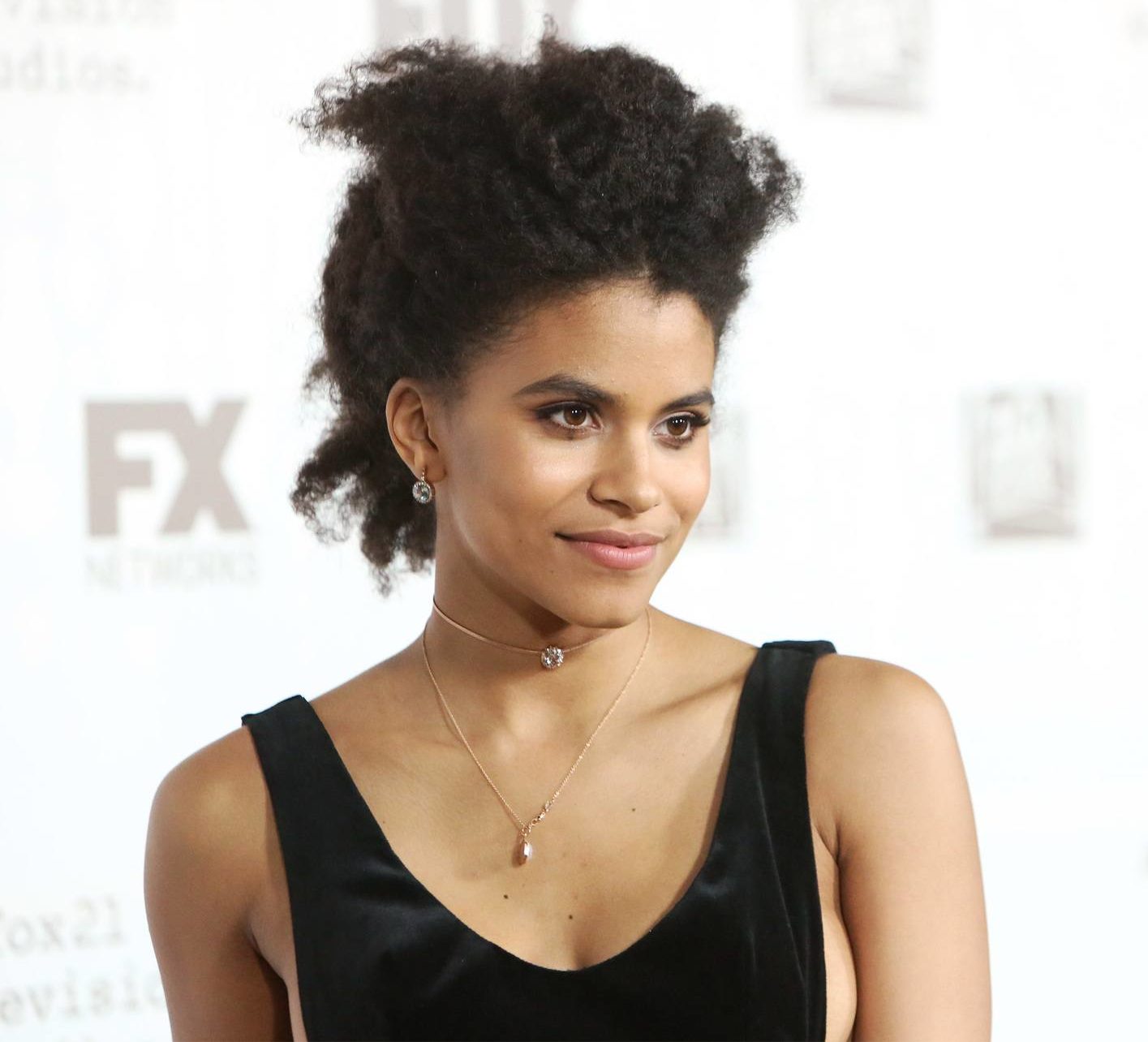 Curly hair hairstyles: Zazie Beerz with naturally afro curly hair styled pinned back with a quiff on red carpet wearing a black tank top