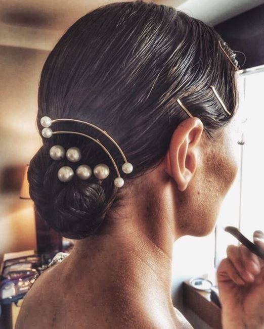 side view of dark brown hair in low sleek bun with pearl hair accessories