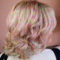 side profile of a woman with bob length curly blonde hair with pastel coloured confetti dye