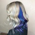 woman with shoulder length wavy blonde hair with a geode hair blue and purple under layer