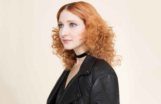 a look of a curly red hair woman wearing black leather jacket