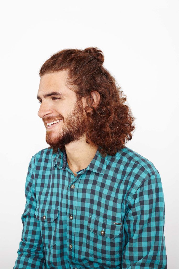 half up top knot on man with curly brown hair