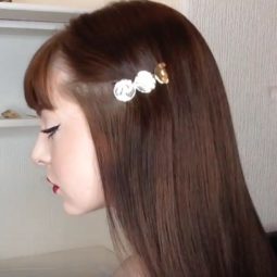side view of beauty vlogger Mostly Megan with long brown hair and a fringe, wearing a silver hair slide