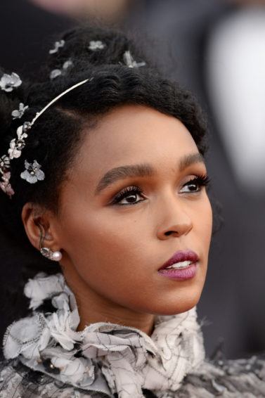 close up shot of janelle with space bun afro hairstyle that has accessories in it, wearing ruffled dress