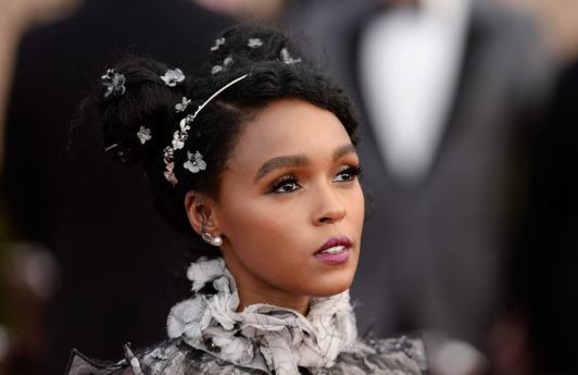 close up shot of janelle with space bun afro hairstyle that has accessories in it, wearing ruffled dress